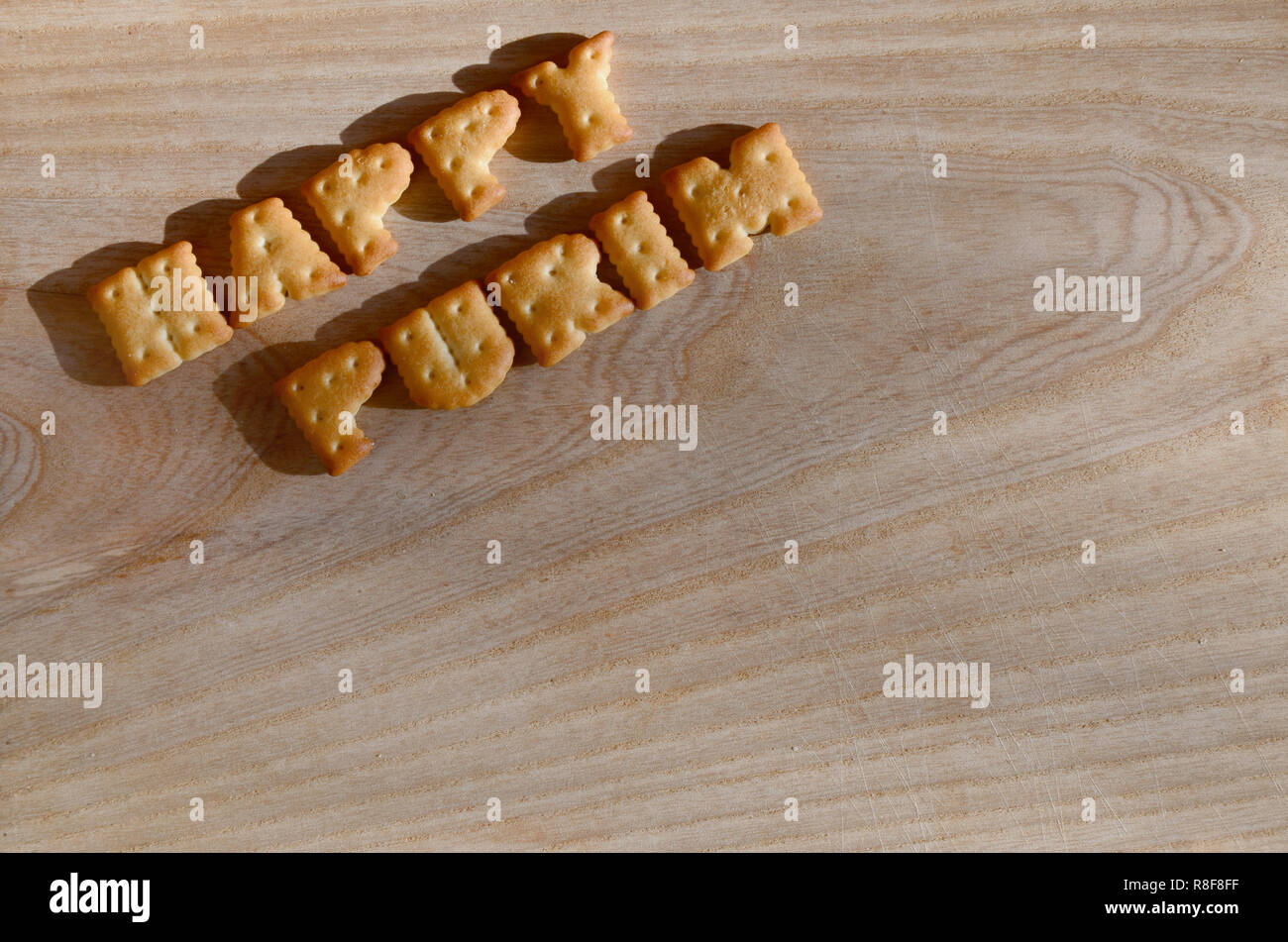 Happy Purim. Von der salzigen Cracker Text als gedruckte Englische Briefe, die auf einer hölzernen Schneidebrett liegen. Nachricht, gesäumt mit essbare Buchstaben Stockfoto