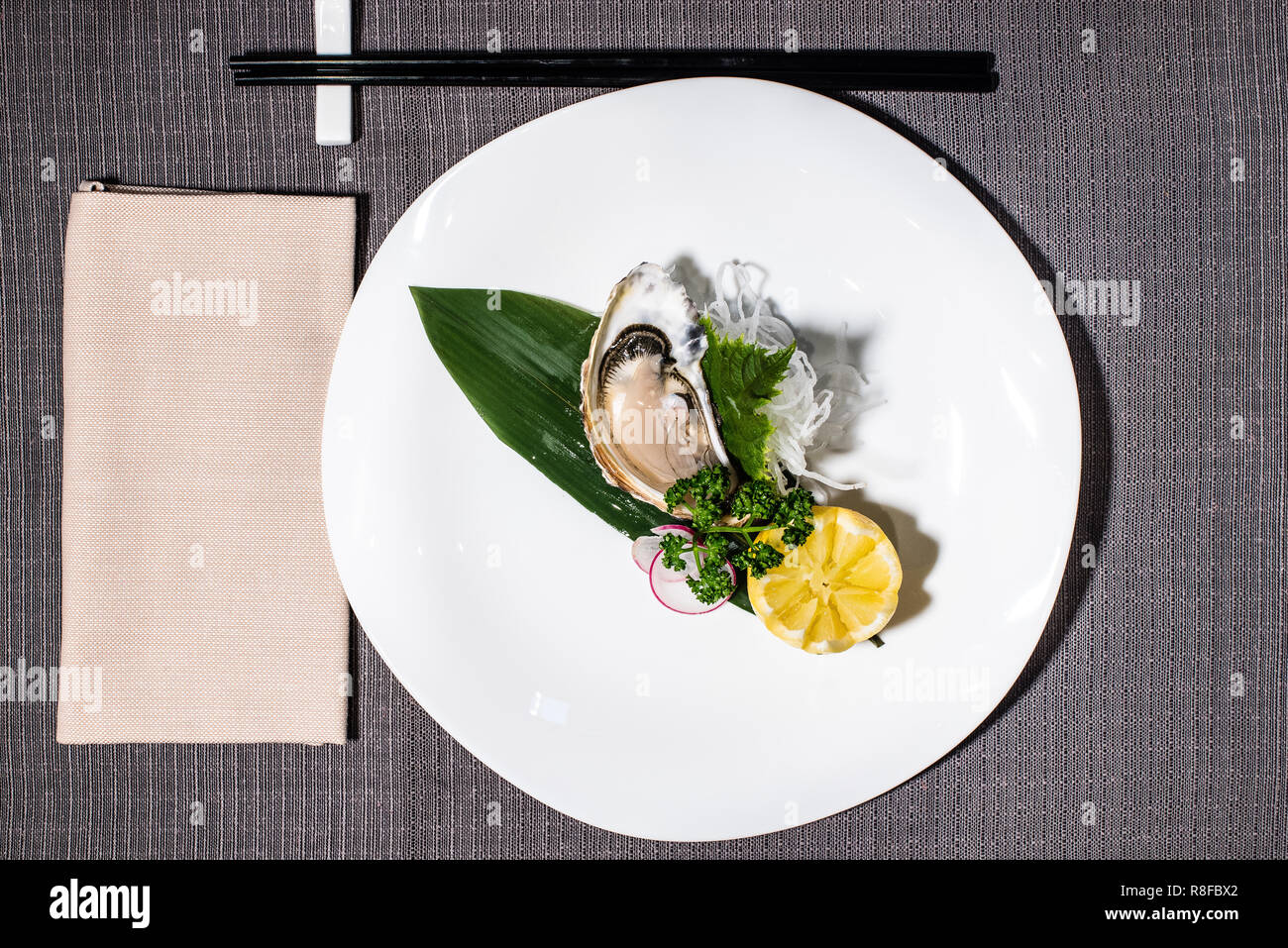Französische Auster, gewürzt mit Zitrone, Dekoration mit daikon Rettich und Julienne Stockfoto