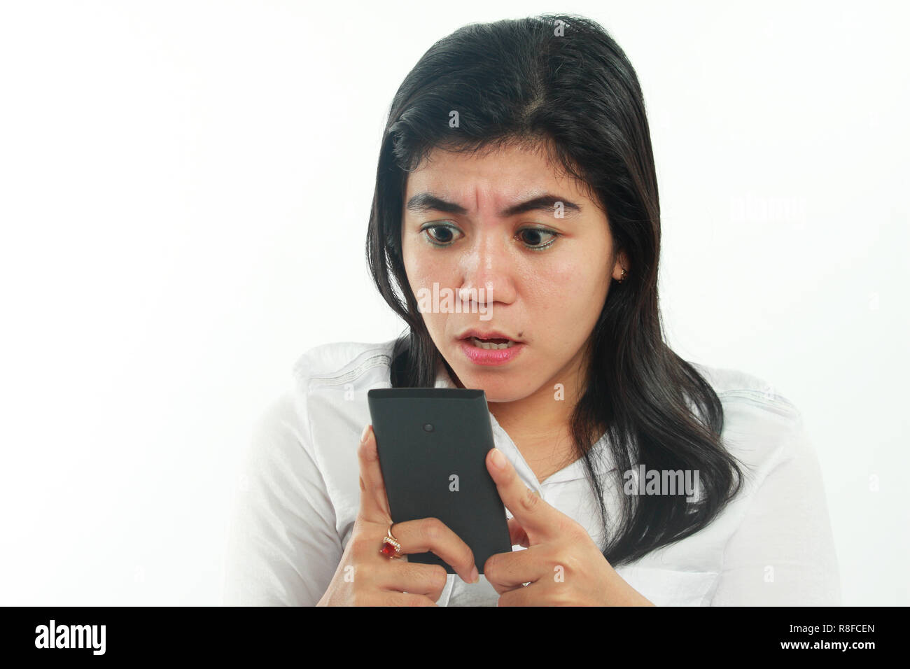 Foto Portrait von eine nette junge asiatische Frau mit Mole sah schockiert und traurig schlechte Nachrichten auf Ihrem Smartphone zu erhalten. Halten Sie das Telefon mit beiden Händen Stockfoto