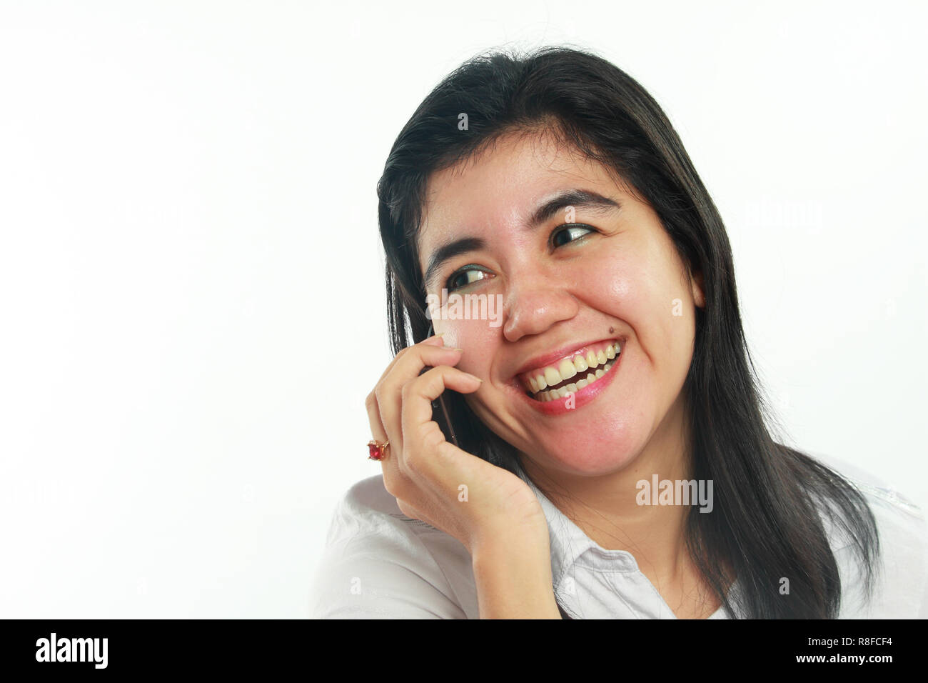 Foto Portrait von eine nette junge asiatische Frau mit Mole sah sehr glücklich und lächelnd beim Gespräch mit ihrem Freund am Telefon auf weißem Hintergrund Stockfoto