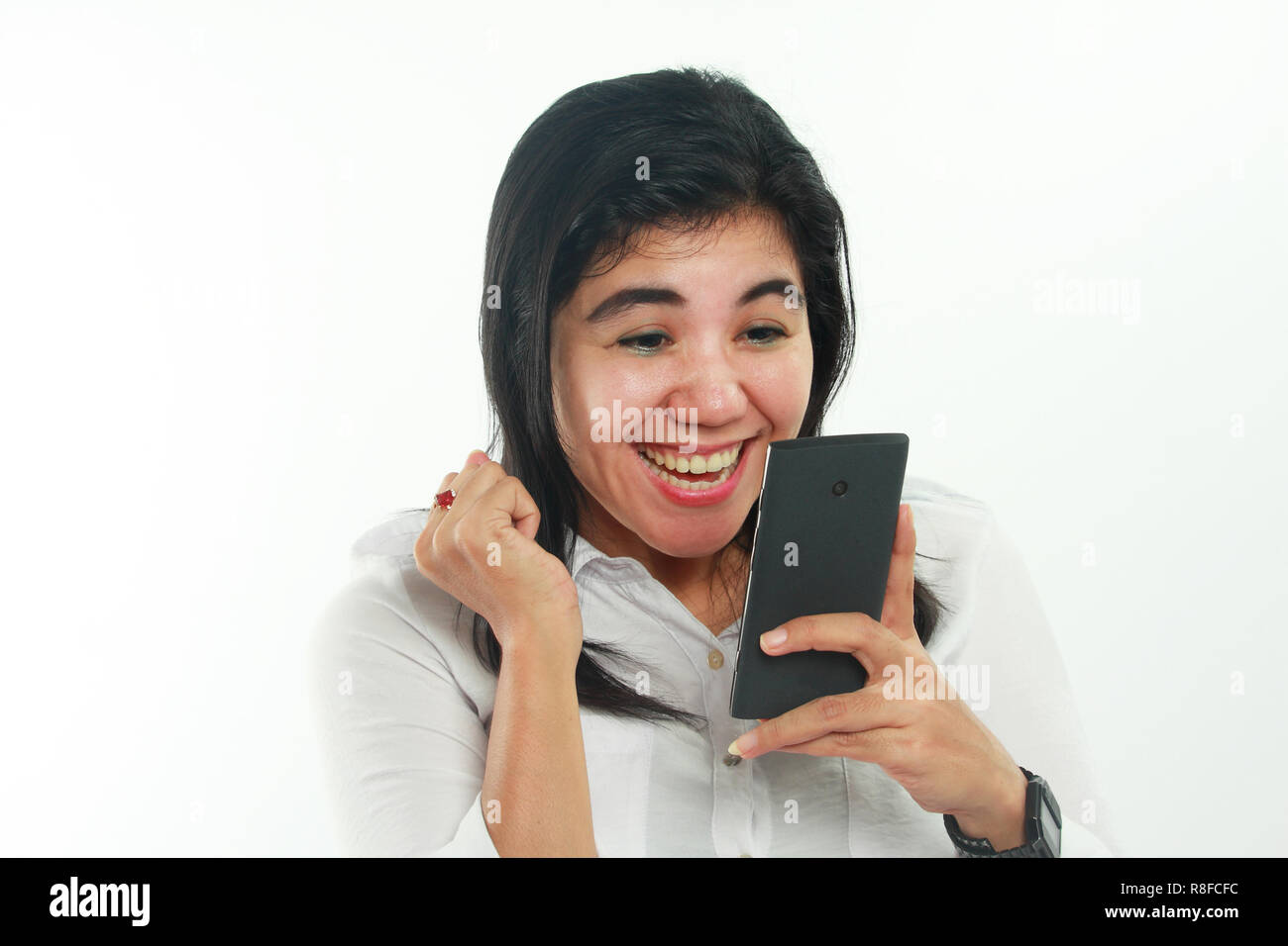 Foto Portrait von eine nette junge asiatische Frau sah sehr fröhlich, lächelnd und verlassen gute Nachrichten auf Ihrem Smartphone zu erhalten. Gewinnender Geste Stockfoto