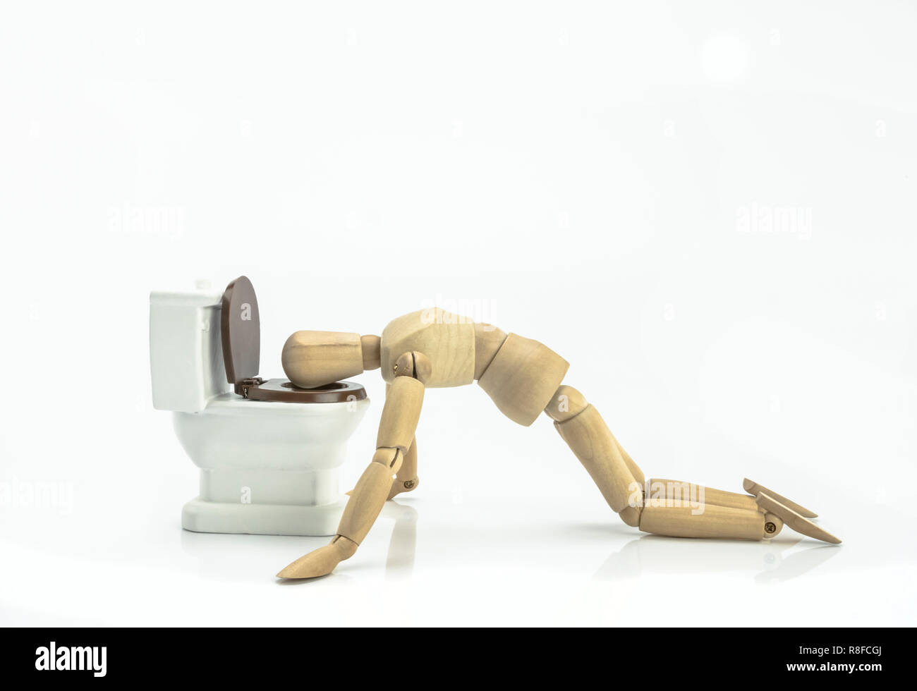 Puppe Holz erbricht sich in einer Toilette auf weißem Hintergrund Stockfoto