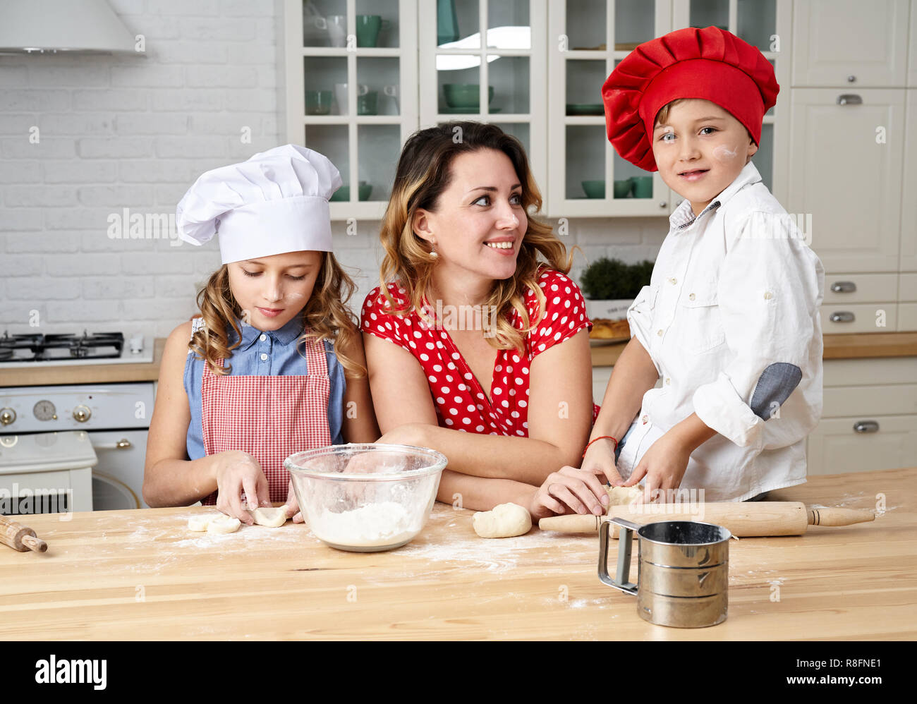 Glückliche Mutter mit lustigen Kinder bereiten den Teig, Backen Sie Plätzchen in der Küche Stockfoto