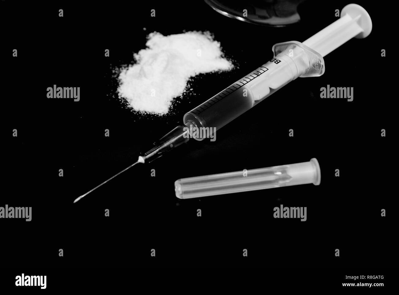 Klassische transparente medizinische Spritze mit einem narkotischen Flüssigkeit auf einem dunklen Hintergrund und Pulver Stockfoto
