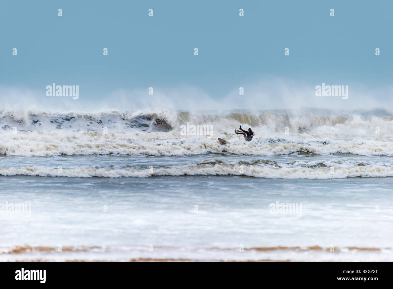 Ein Surfer verliert die Kontrolle, wie er von den Wellen an einem Wintertag in Westward Ho in den Schatten gestellt! Strand in North Devon. Stockfoto