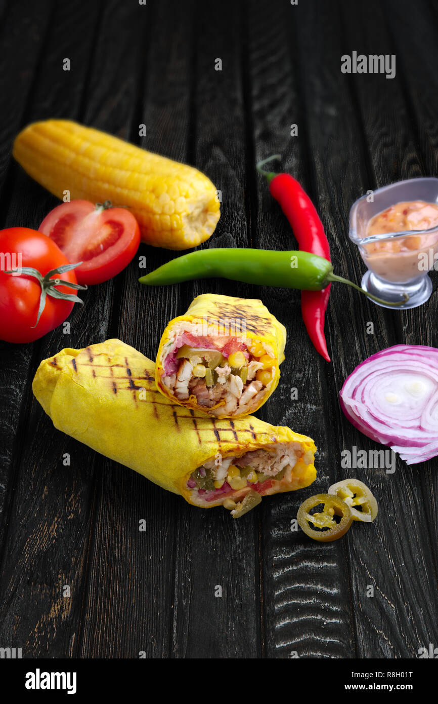 Spicy Chili mexikanische Burrito. Lavash mit Hühnchen, Mais, Salat, Tomaten, Zwiebel und jalapeno Stockfoto
