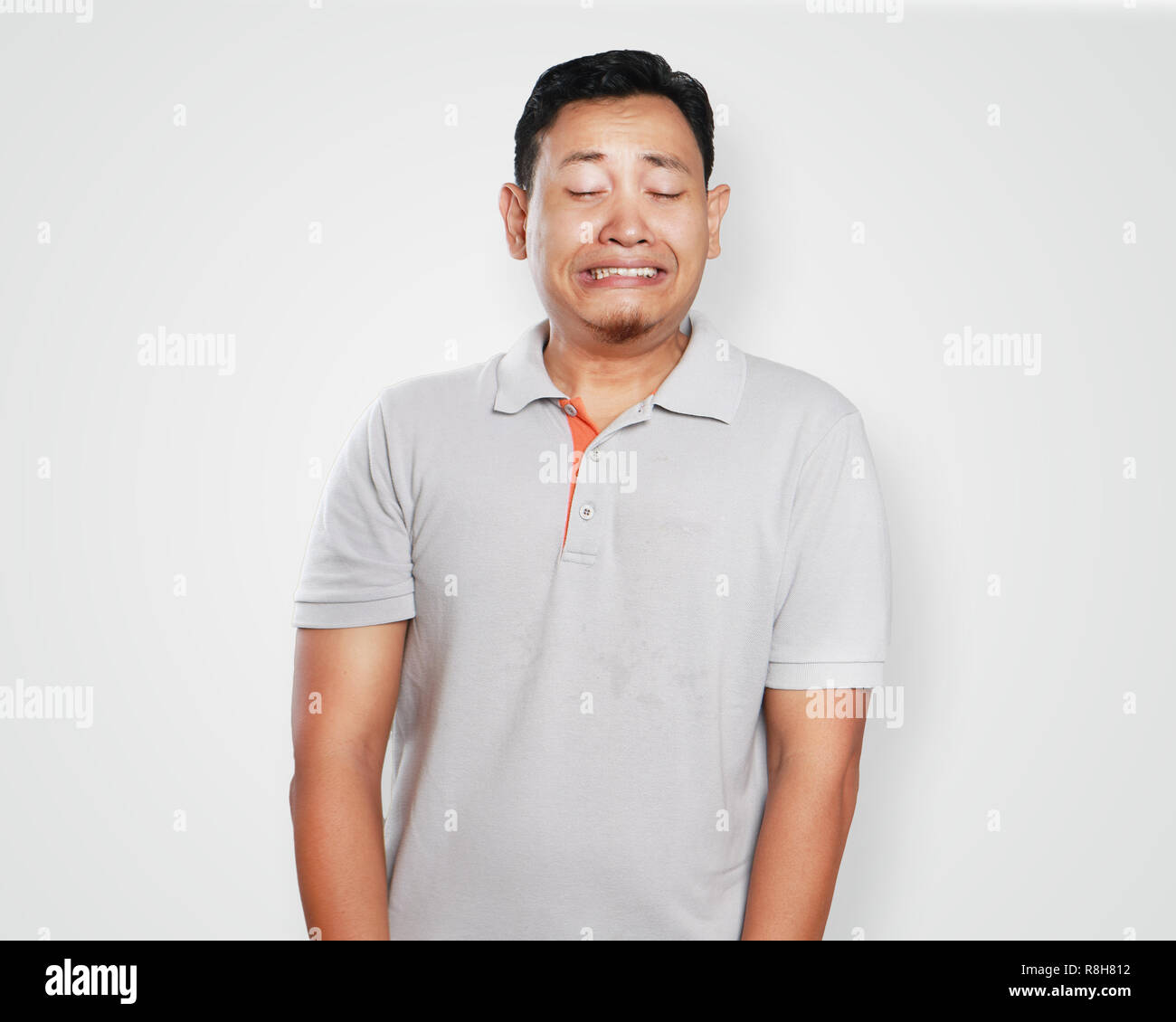 Foto Portrait von einem netten gutaussehenden jungen asiatischen Mann in Schmerz weinen und nach unten schaut, schmerzhafte Geste Stockfoto