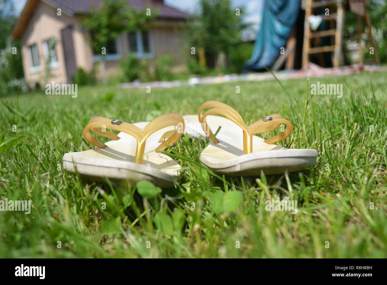 Selektiver Fokus Sommer Konzept, Gummi Hausschuhe im Gras in der Nähe von Cottage Stockfoto