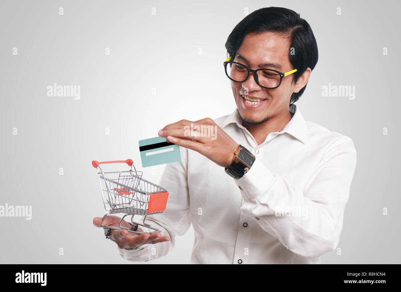 Foto Bild Portrait einer Lustig junge asiatische Geschäftsmann auf der Suche glücklich und lächelnd, während sie eine Kreditkarte in einem kleinen Einkaufswagen, Nahaufnahme Stockfoto