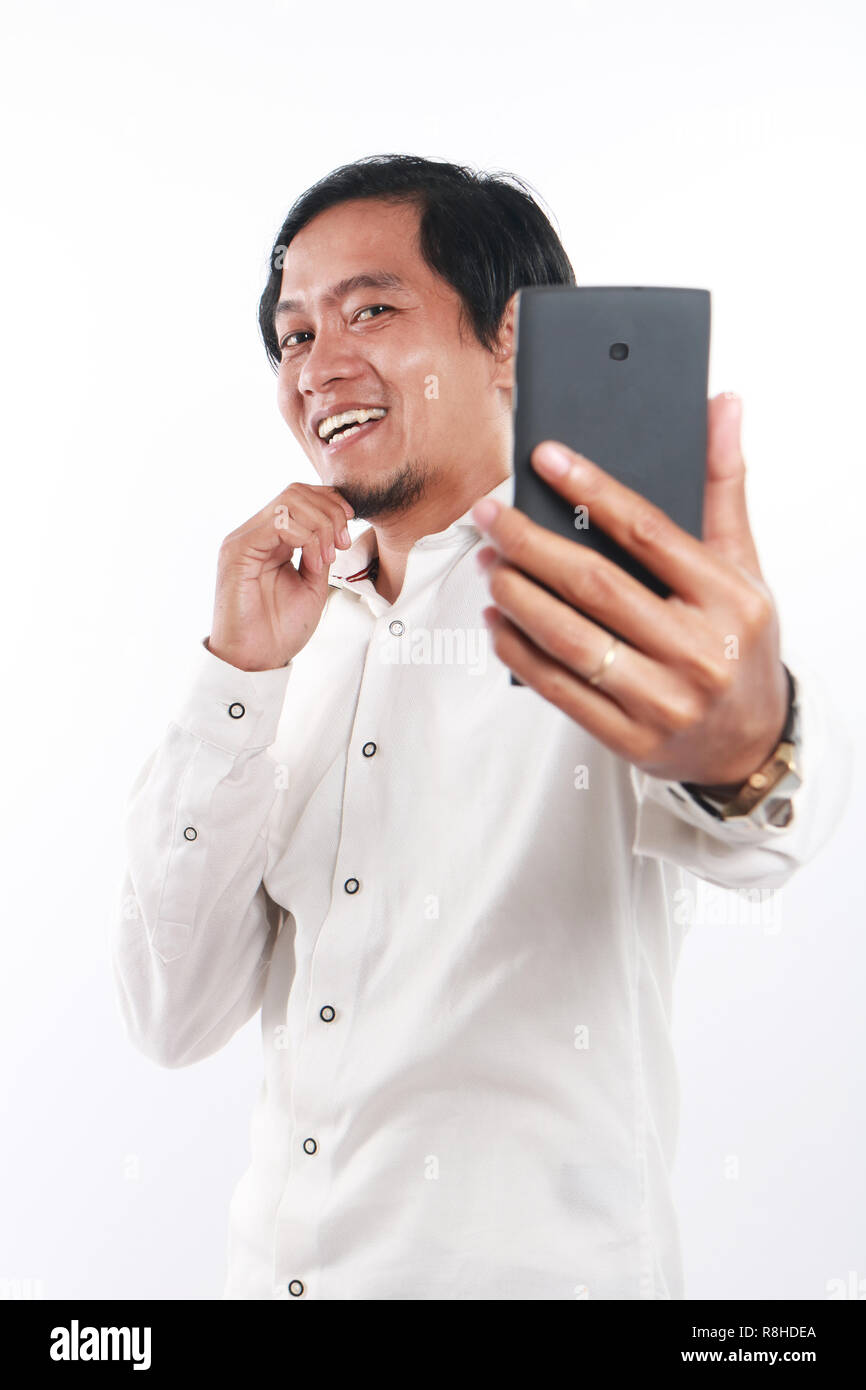 Foto Bild Portrait einer Lustig junge asiatische Geschäftsmann sah glücklich und lächelnd während der Einnahme von selfie Foto von selbst auf seinem Smartphone, bis por schließen Stockfoto