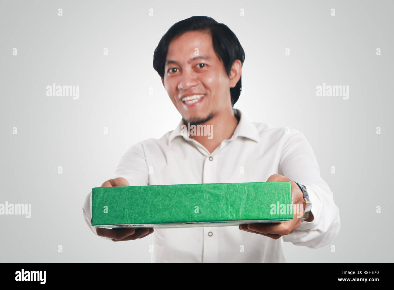 Foto Portrait eines lustigen jungen asiatischen Mann glücklich lächelnd mit großen Augen geöffnet, während die grünen Geschenkpaket box Stockfoto