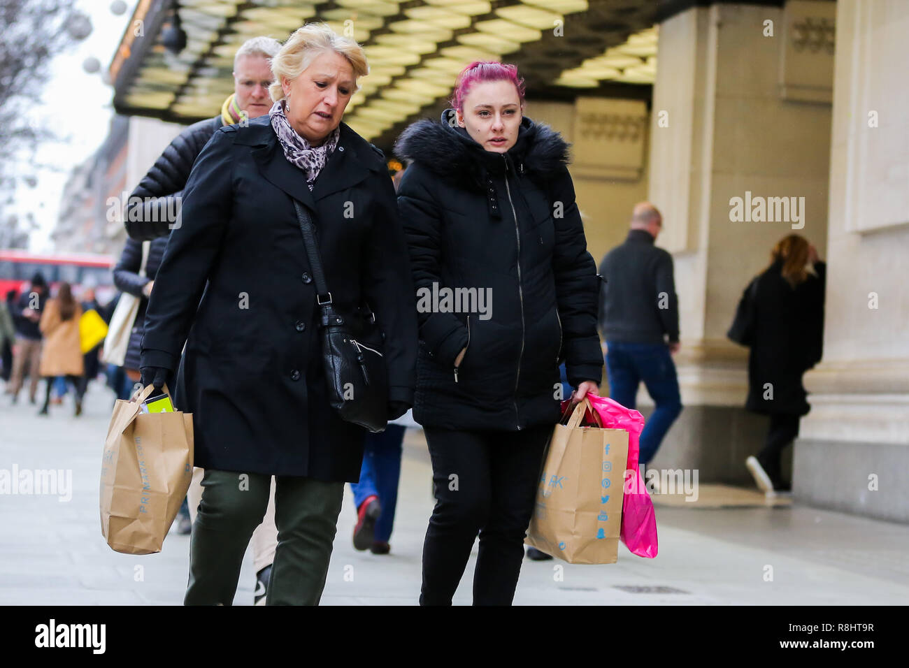 Frauen sind mit Primark Taschen an der Londoner Oxford Street mit Tüten mit 9 Tage zu Weihnachten gesehen. Händler rechnen mit einem Ansturm der Käufer in der Leitung - bis zu Weihnachten. Stockfoto