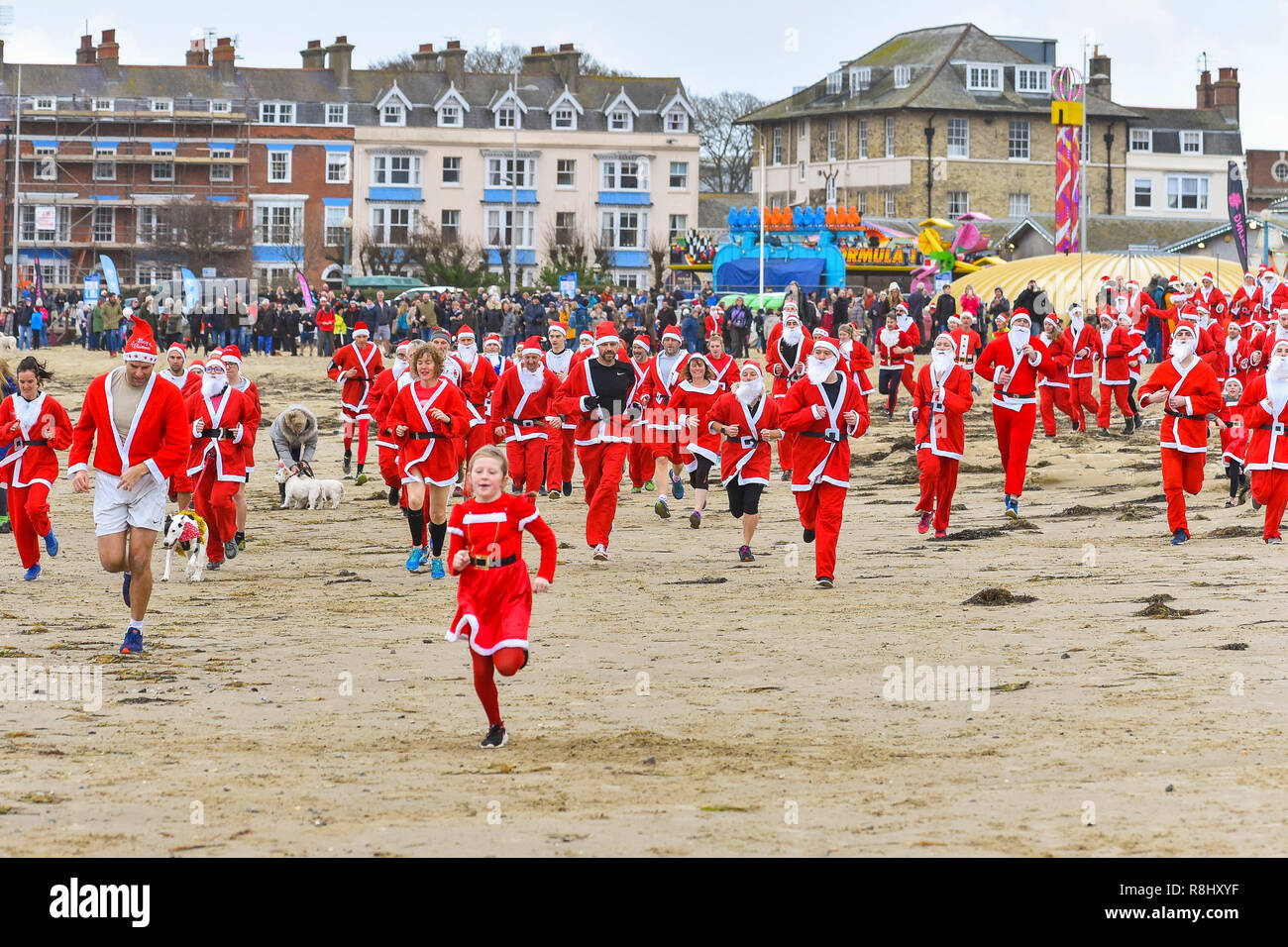 Dorchester, Dorset, Großbritannien. 16. Dezember 2018. Jährliche Verfolgung der Pudding Rennen am Strand von Weymouth in Dorset. Hunderte von Konkurrenten in santa Kostüme gekleidet jagen einen Läufer als plumpudding am Strand entlang nach Bowleaze und wieder angezogen. Foto: Graham Jagd-/Alamy leben Nachrichten Stockfoto