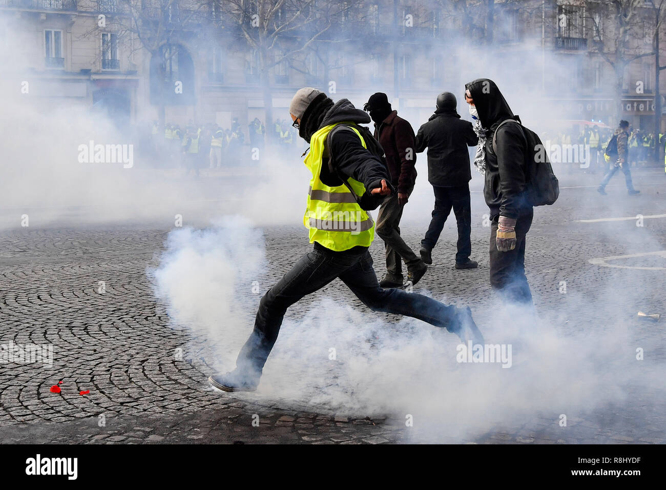 Paris, Frankreich. 8 Dez, 2018. Eine Demonstrantin tritt eine Träne Shell in der Nähe des Arc de Triomphe in Paris, Frankreich, am 8. Dezember, 2018. Credit: Chen Yichen/Xinhua/Alamy leben Nachrichten Stockfoto