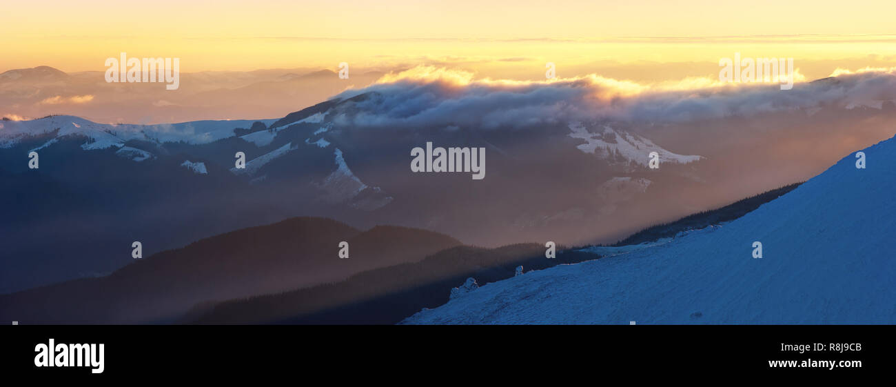 Bergpanorama mit schönen Wolken und den Sonnenuntergang. Winterlandschaft mit einem Spitzenwert Stockfoto