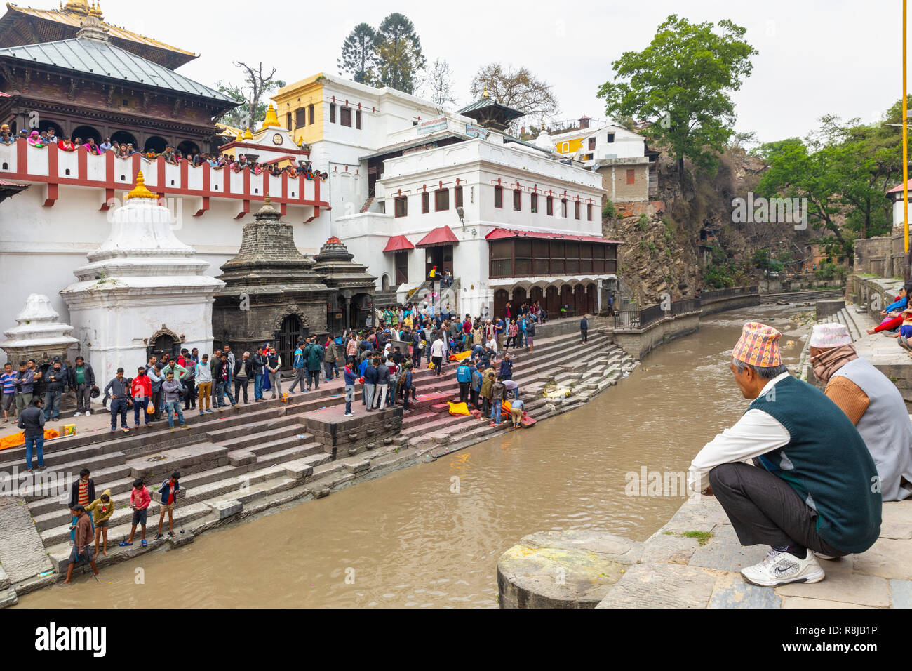 Leute beobachten ein Hindu Beerdigung auf der Ghat auf den Bagmati River am Heiligen hinduistischen Pashupatinath Tempel in Kathmandu, Nepal Stockfoto