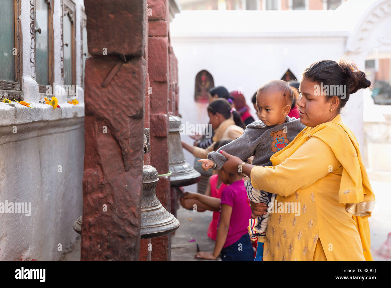 Nepali Frau und Sohn berühren Klingel an der Boudhanath Stupa in Kathmandu, Nepal Stockfoto
