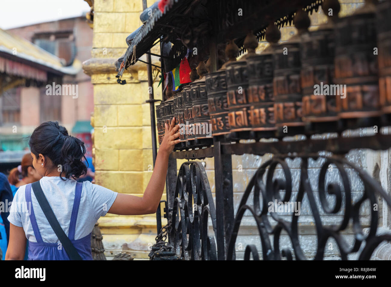 Einzelne junge Frau sich drehende Gebetsmühle am Swayambhunath (Monkey Tempel), Kathmandu, Nepal, Asien Stockfoto