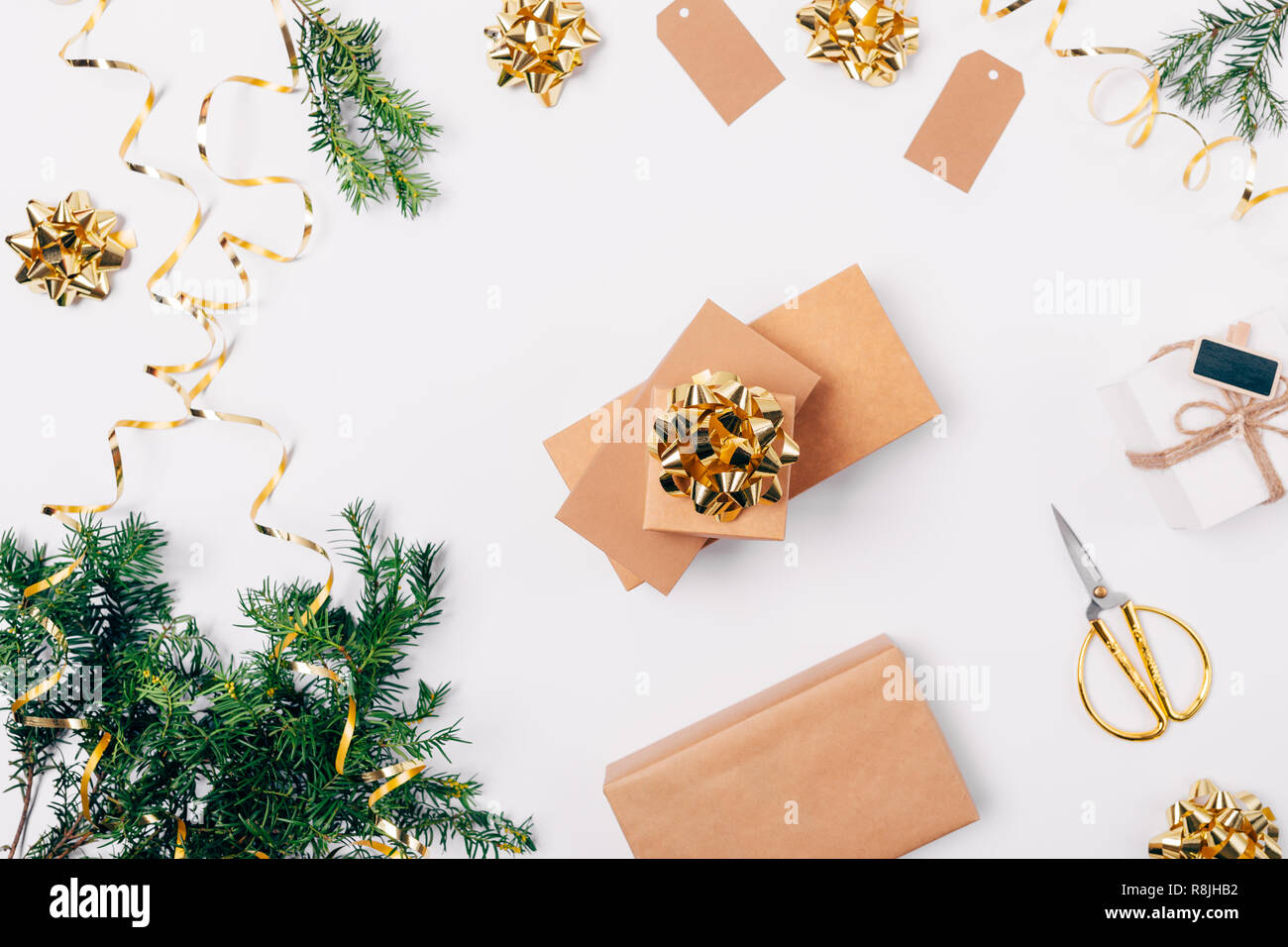 Stapel von geschenkboxen unter Festliche flach Zusammensetzung von Weihnachten goldene Verzierungen und Tannenzweigen auf weißem Hintergrund, Ansicht von oben. Stockfoto
