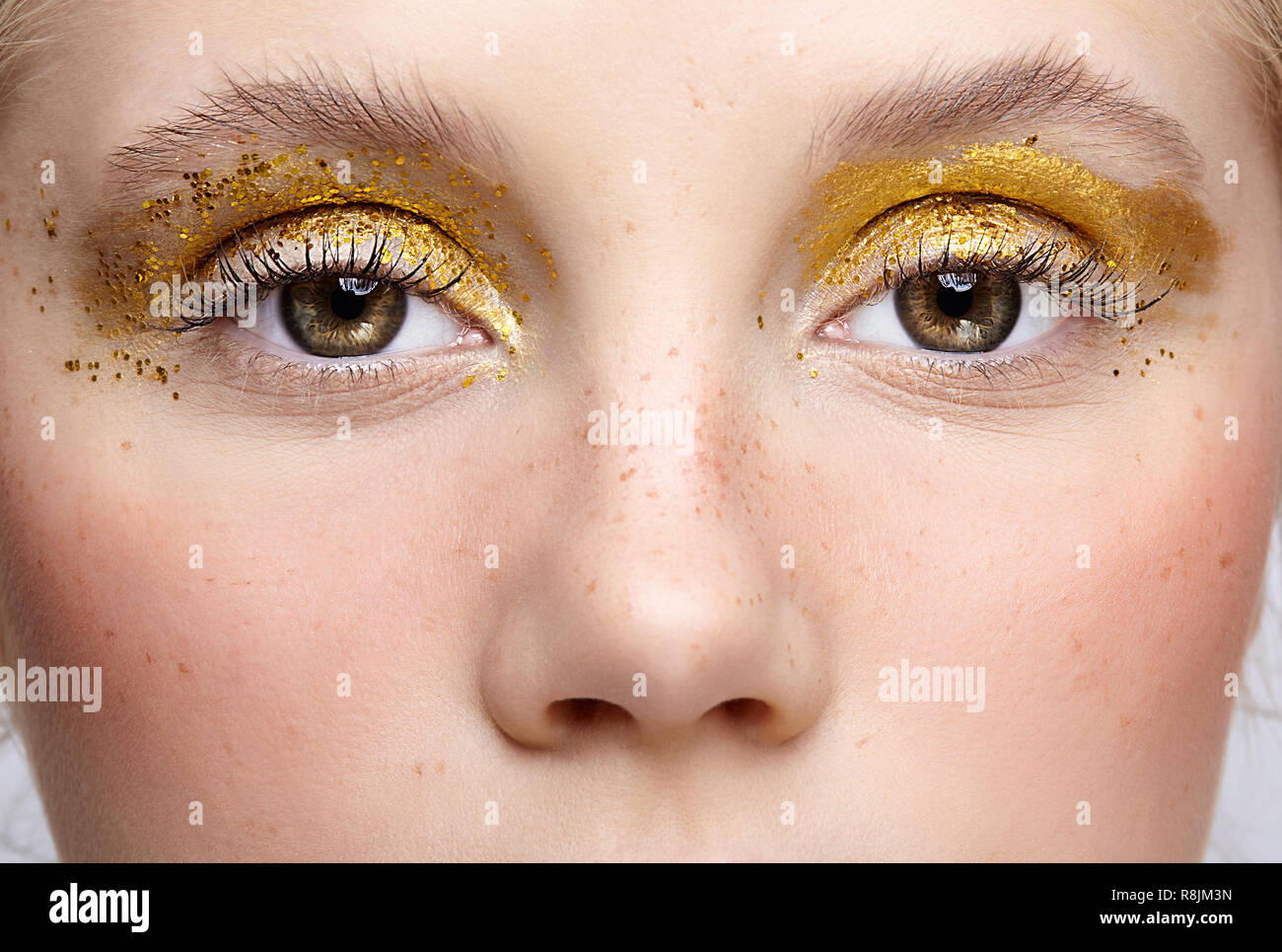 Nahaufnahme Makroaufnahme der menschlichen weiblichen Auge. Frau mit ungewöhnlichen Funkeln glitzernde vogue Gesicht Beauty Makeup. Mädchen mit perfekte Haut und gelbe rauchigen Augen Auge Stockfoto