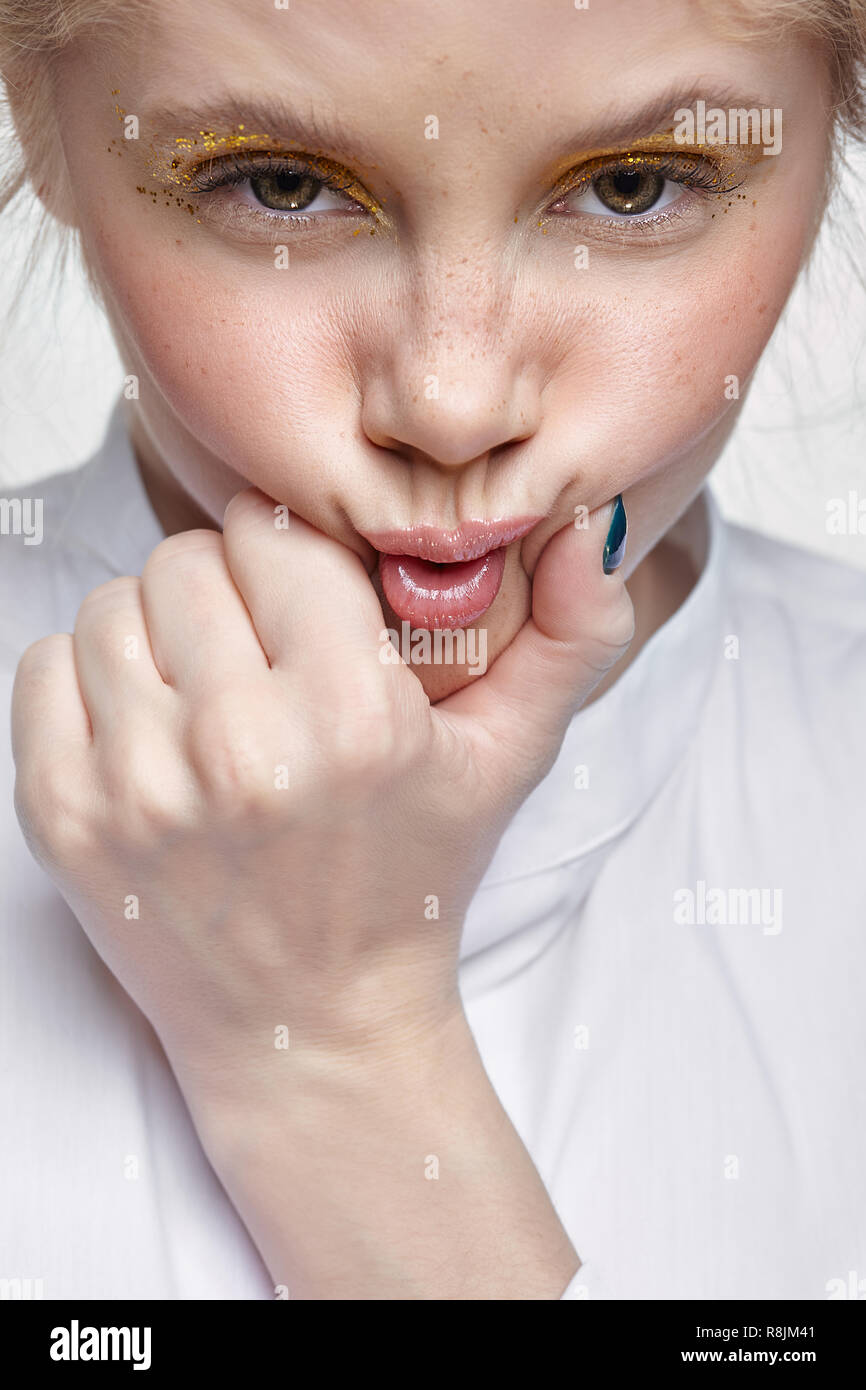 Emotionales Porträt einer jungen blonden Frau auf grauem Hintergrund. Weibliche quetscht Gesicht Mund von Hand Stockfoto