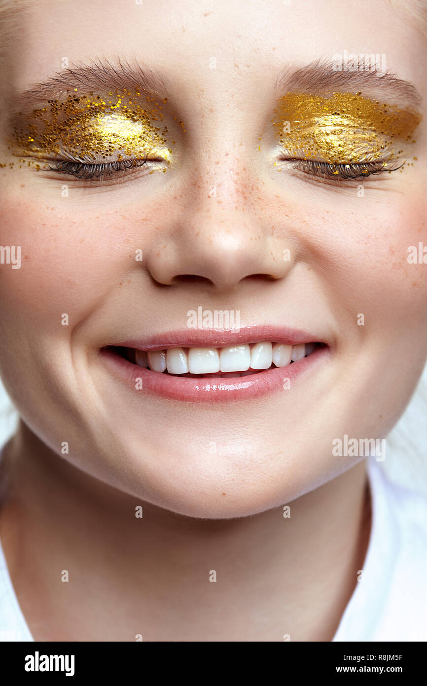 Lächelnd weibliche Gesicht mit geschlossenen Augen. Frau mit ungewöhnlichen Funkeln glitzernde vogue Gesicht Beauty Makeup. Mädchen mit perfekte Haut und gelbe rauchigen Augen Auge sha Stockfoto