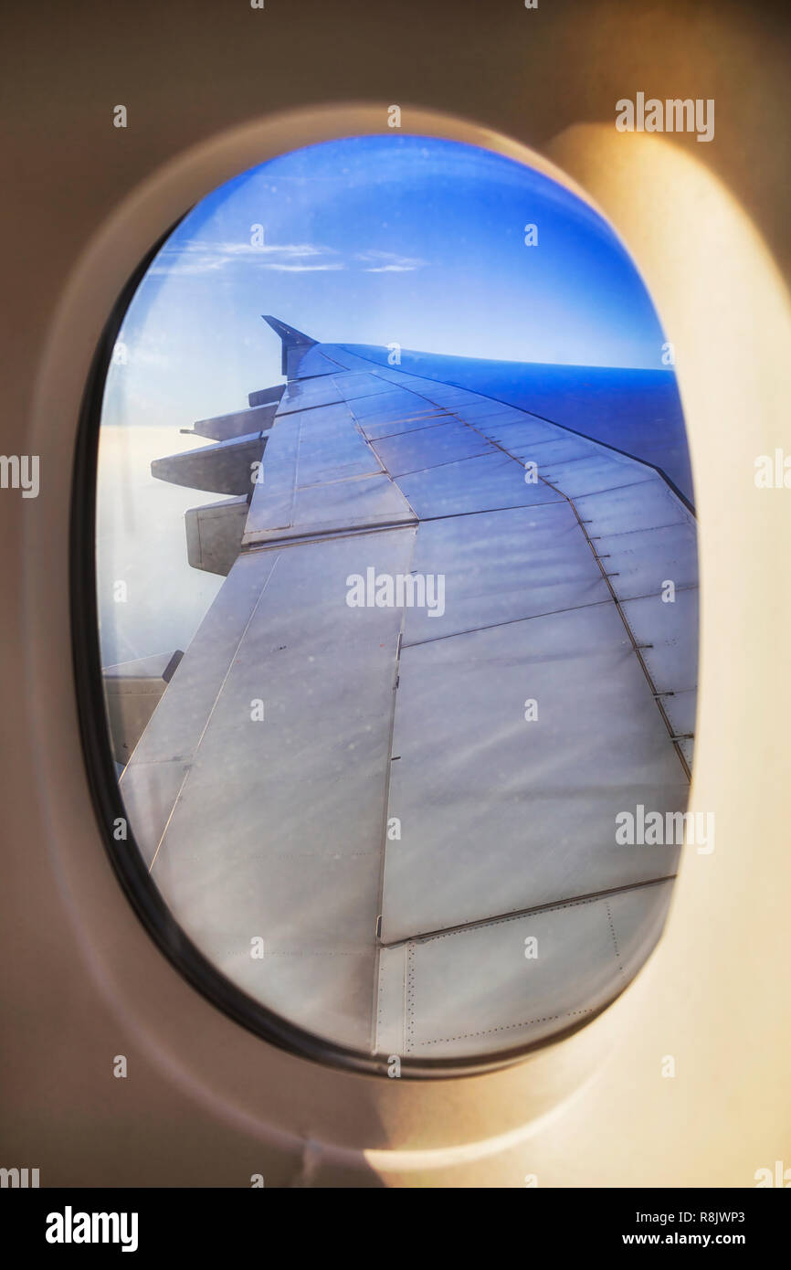 Oval von offenen Anzeigen des Fensters der Beifahrerseite mit der Oberfläche der Flugzeugflügel und Motoren hohe in der Stratosphäre bei Langstreckenflug im blauen Himmel. Stockfoto