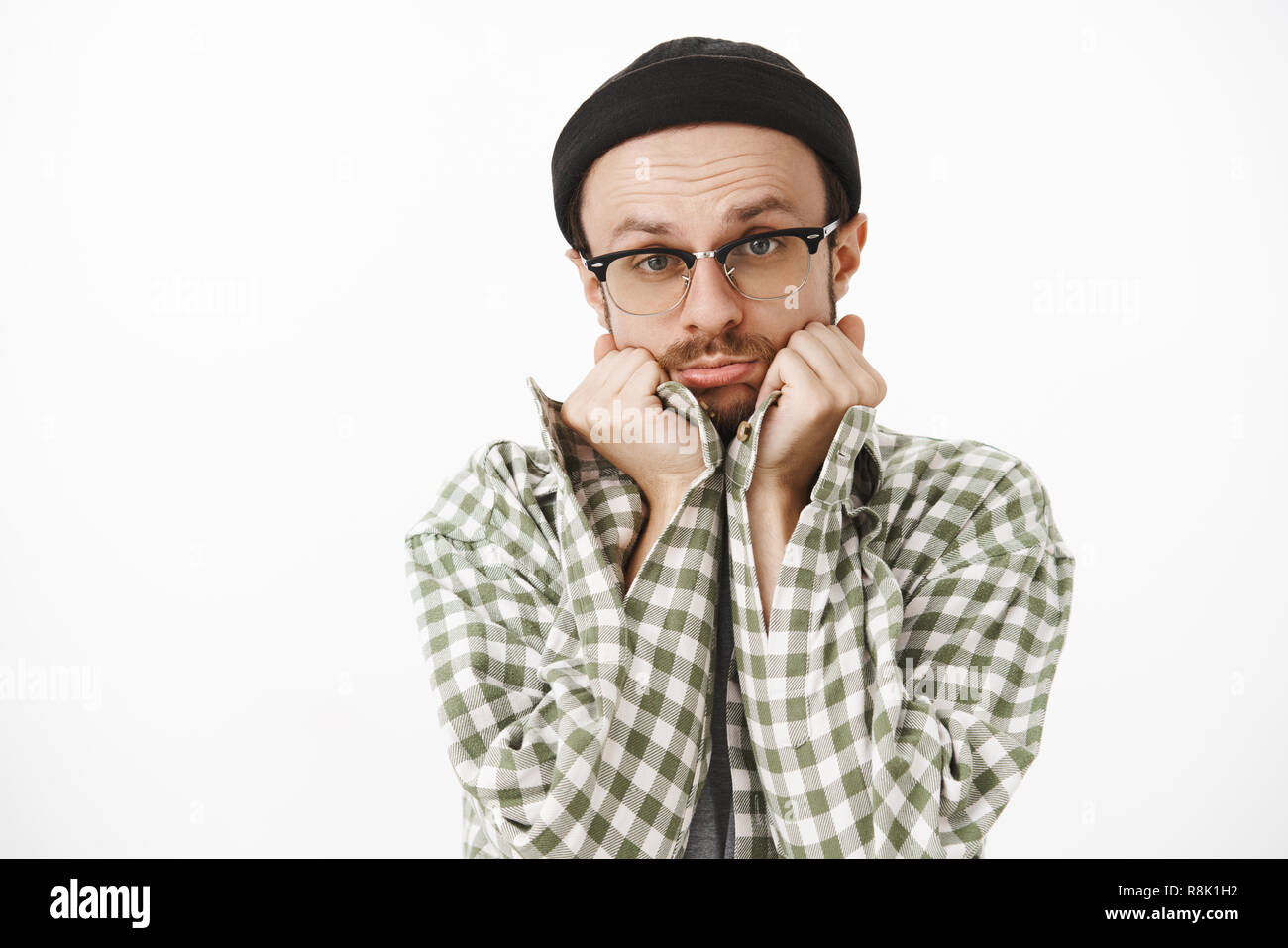 Nahaufnahme des dummen niedlich aussehenden Freund in Schwarz beanie Brillen und Grünen kariertes Hemd schiefen Kopf auf Palmen Schmollen und Falten Lippen, zärtlich und unschuldiger Blick an Charme, Freundin Stockfoto