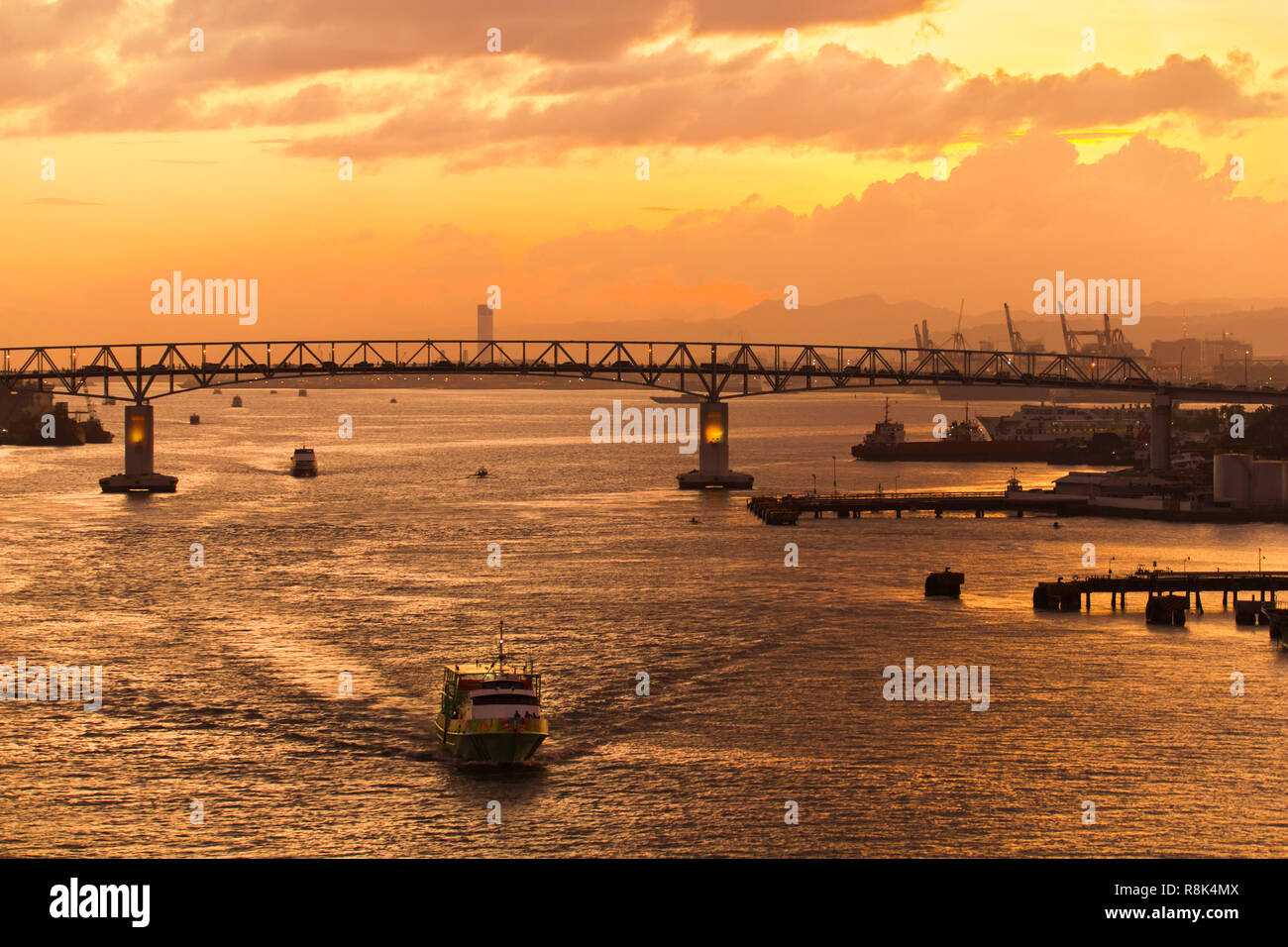 Der Verkehr auf der Brücke und Boote und Fähren Überfahrt an Cebu Mactan Bridge in der Goldenen Dämmerung und Sonnenuntergang an der goldenen Stunde Stockfoto