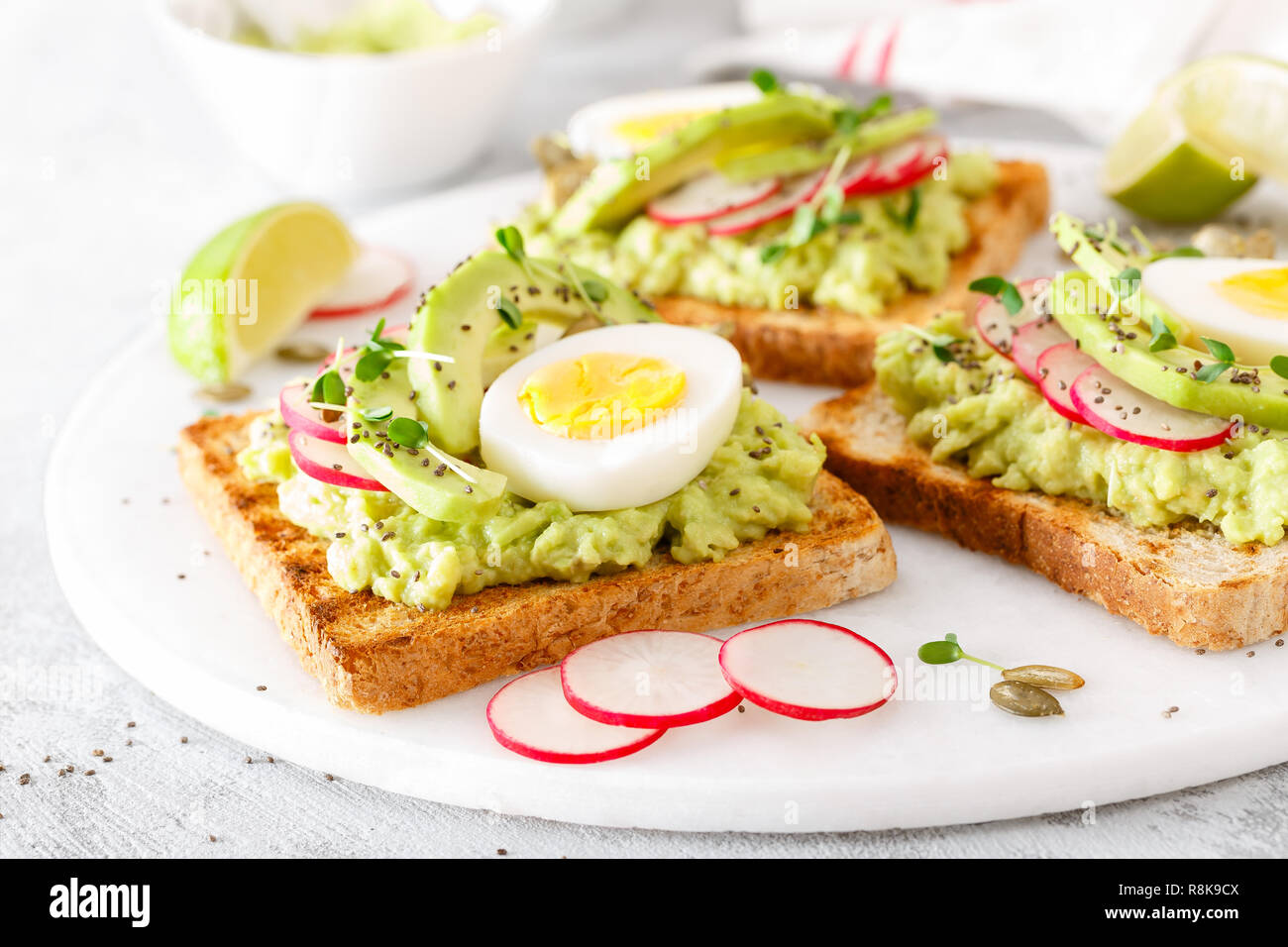 Toast mit Avocado guacamole, frische Radieschen, gekochtes Ei, Chia und Kürbiskernen. Diät Frühstück. Leckere und gesunde pflanzliche Lebensmittel. Nahaufnahme Stockfoto