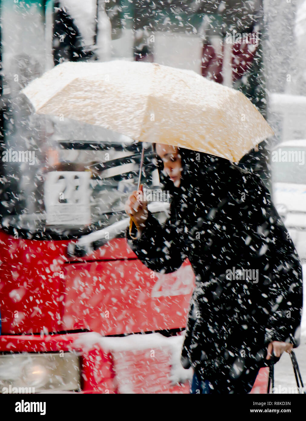 Belgrad, Serbien - Dezember 15, 2018: Eine junge Frau zu Fuß unter dem Dach in starker Schneefall in Stadt Straße vor den Bus Nummer 28. Stockfoto