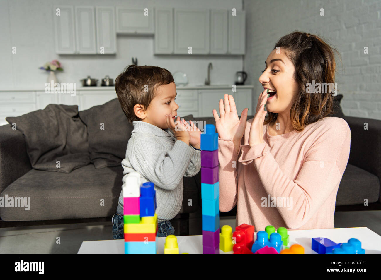 Fröhliche Frau Pat-a-Kuchen mit kleinen Sohn zu Hause Stockfoto