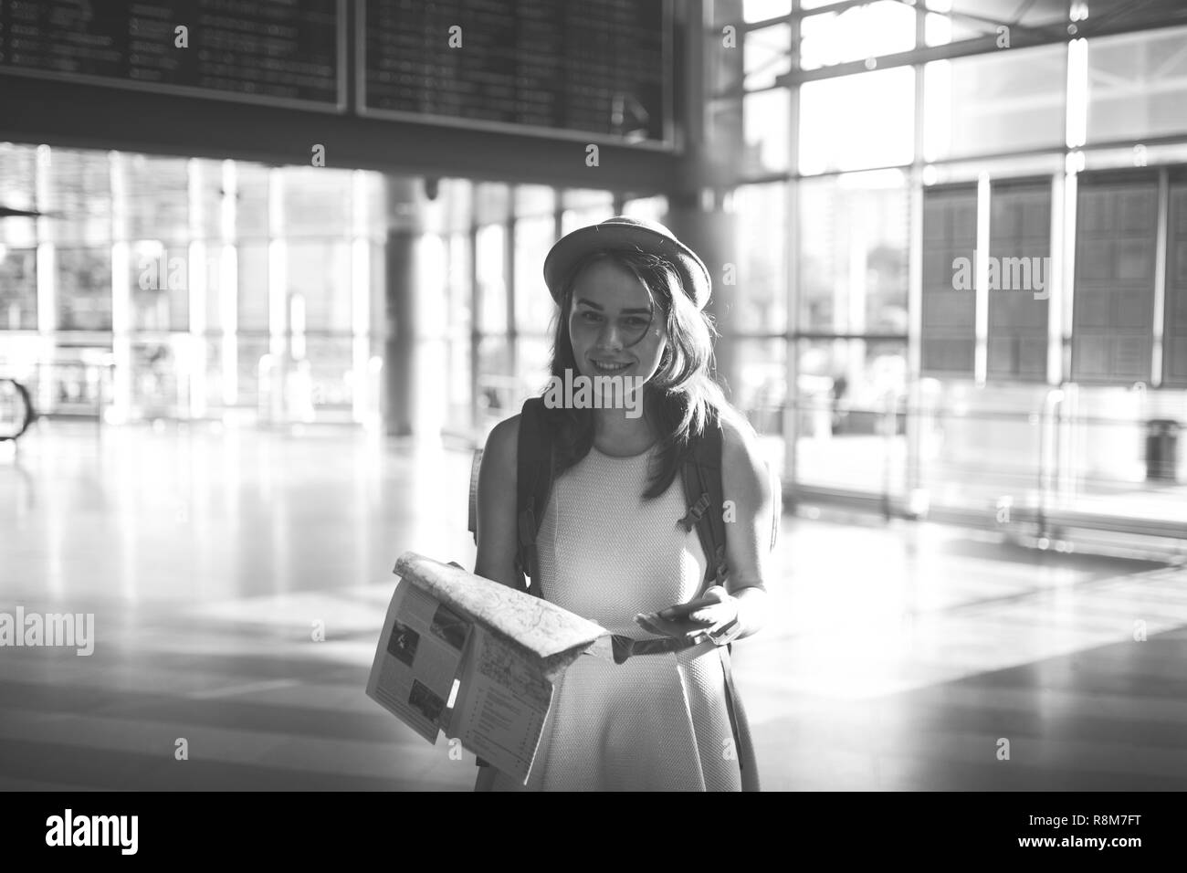 Thema Reisen und Transport. Schönen jungen kaukasischen Frau in Kleid und Rucksack im Bahnhof Terminal mit Blick auf elektronische sc Stockfoto