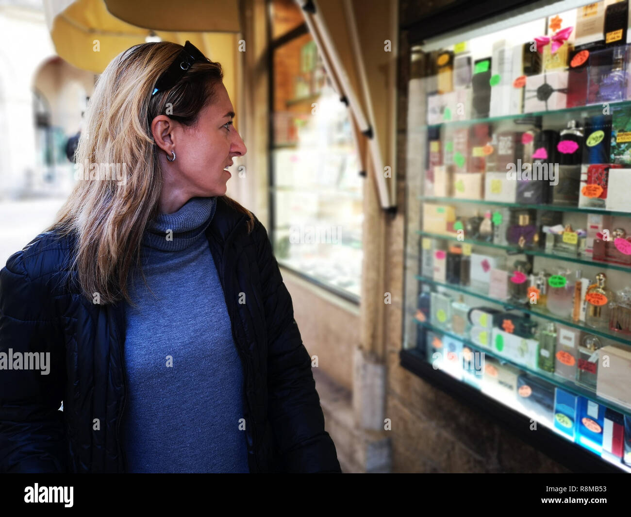 Die Frau, die durch Schaufenster einer Parfümerie Anzeige Schaufenster angezogen Stockfoto