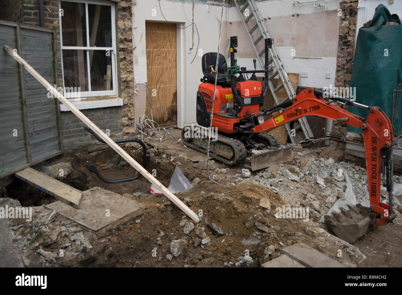 Mechanische digger inmitten der Trümmer einer Baustelle an einem Haus erweitert in Twickenham, Middlesex, England Stockfoto