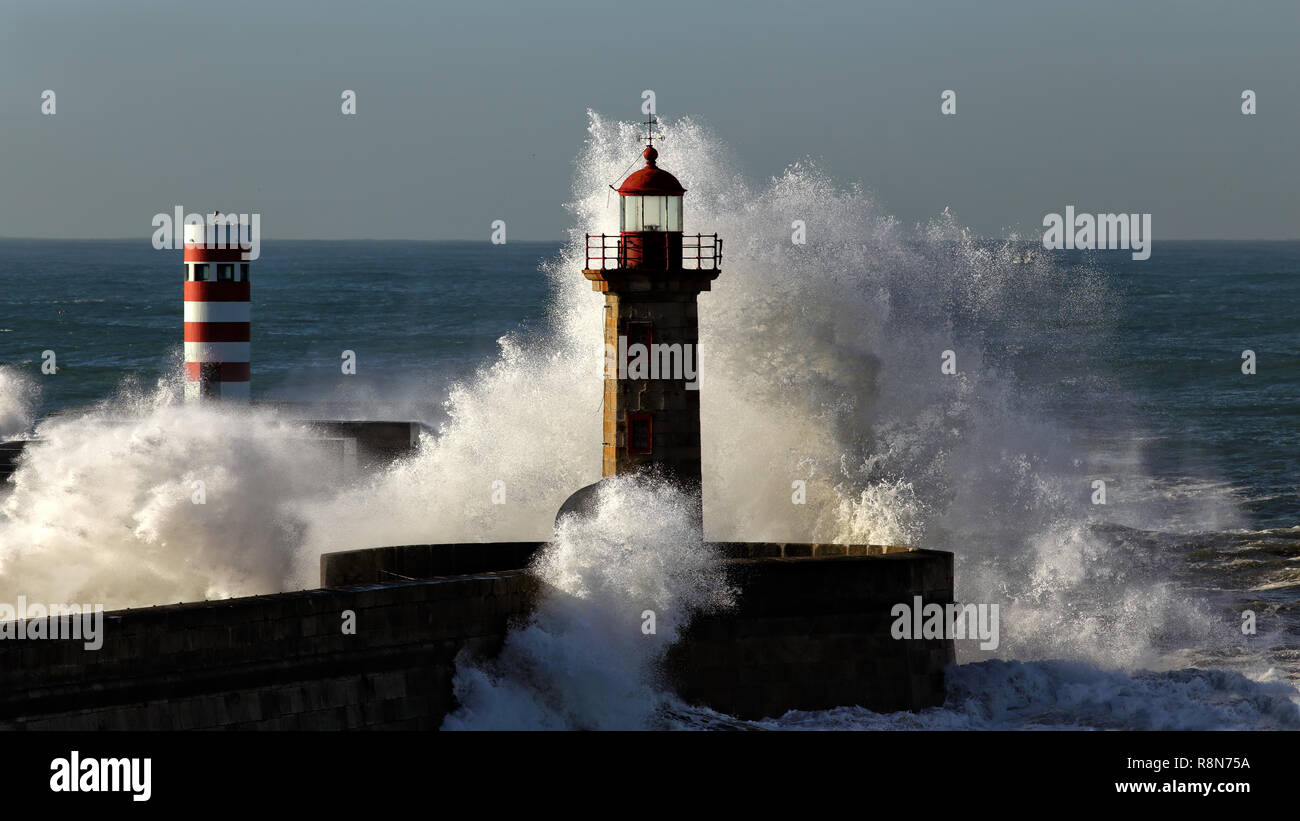Big plätschernden Wellen mit Spray über Piers und Leuchttürme der Fluss Douro Mündung an einem sonnigen Morgen, Porto, Nordportugal Stockfoto