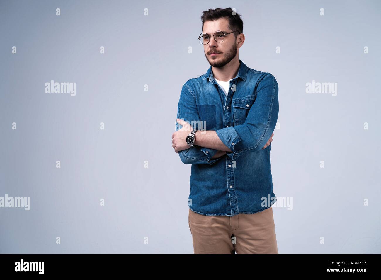 Portrait von gerne modisch gut aussehender Mann in Jeans shirt Kreuzung Hände und an der Kamera schauen. Stockfoto