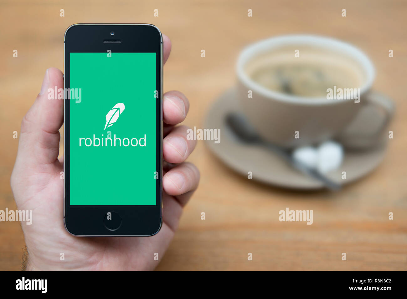 Ein Mann schaut auf seinem iPhone die zeigt die Robinhood Logo (nur redaktionelle Nutzung). Stockfoto