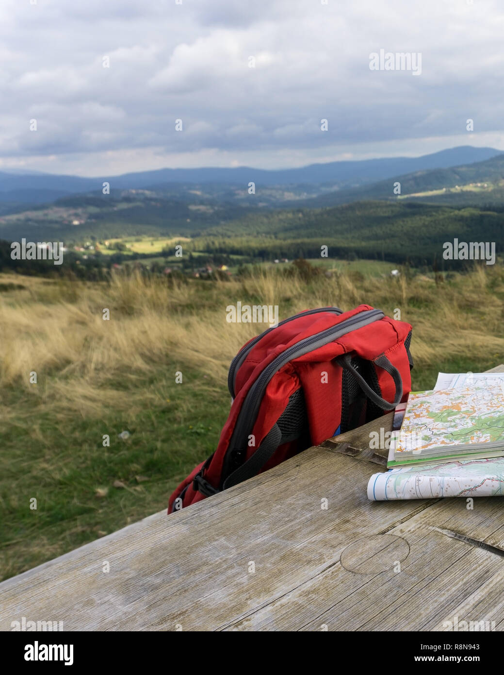 Holzbank mit Wanderkarten und Rucksack. Berglandschaft im Hintergrund, niemand. Die schlesischen Beskiden, Polen. Stockfoto