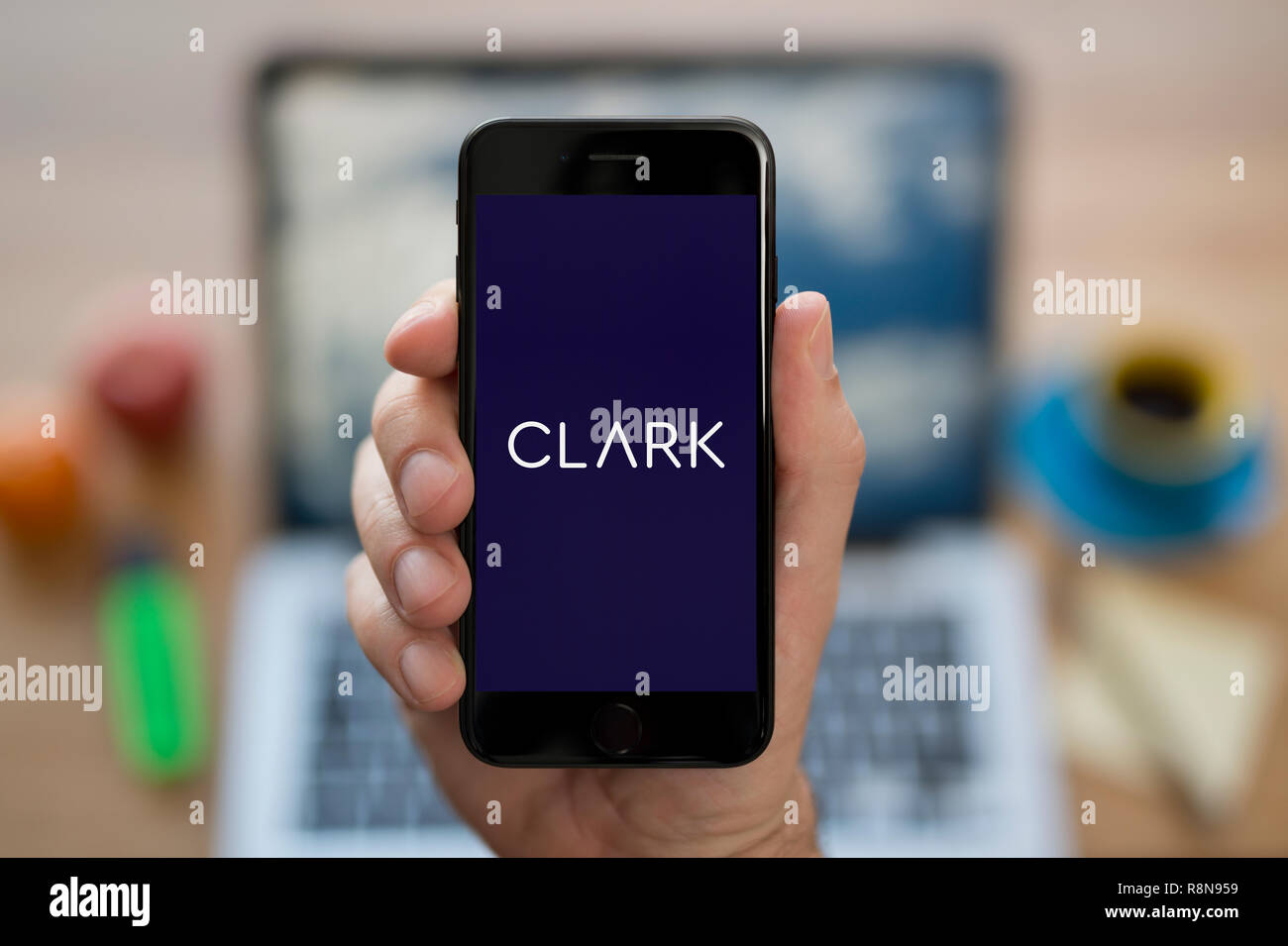 Ein Mann schaut auf seinem iPhone die zeigt die Clark Logo (nur redaktionelle Nutzung). Stockfoto