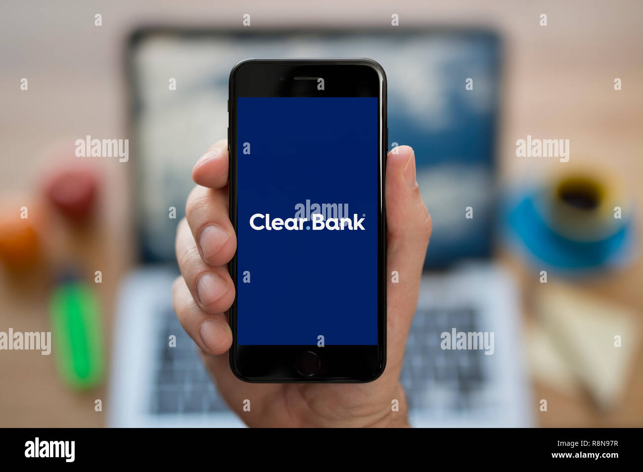 Ein Mann schaut auf seinem iPhone die zeigt die ClearBank Logo (nur redaktionelle Nutzung). Stockfoto
