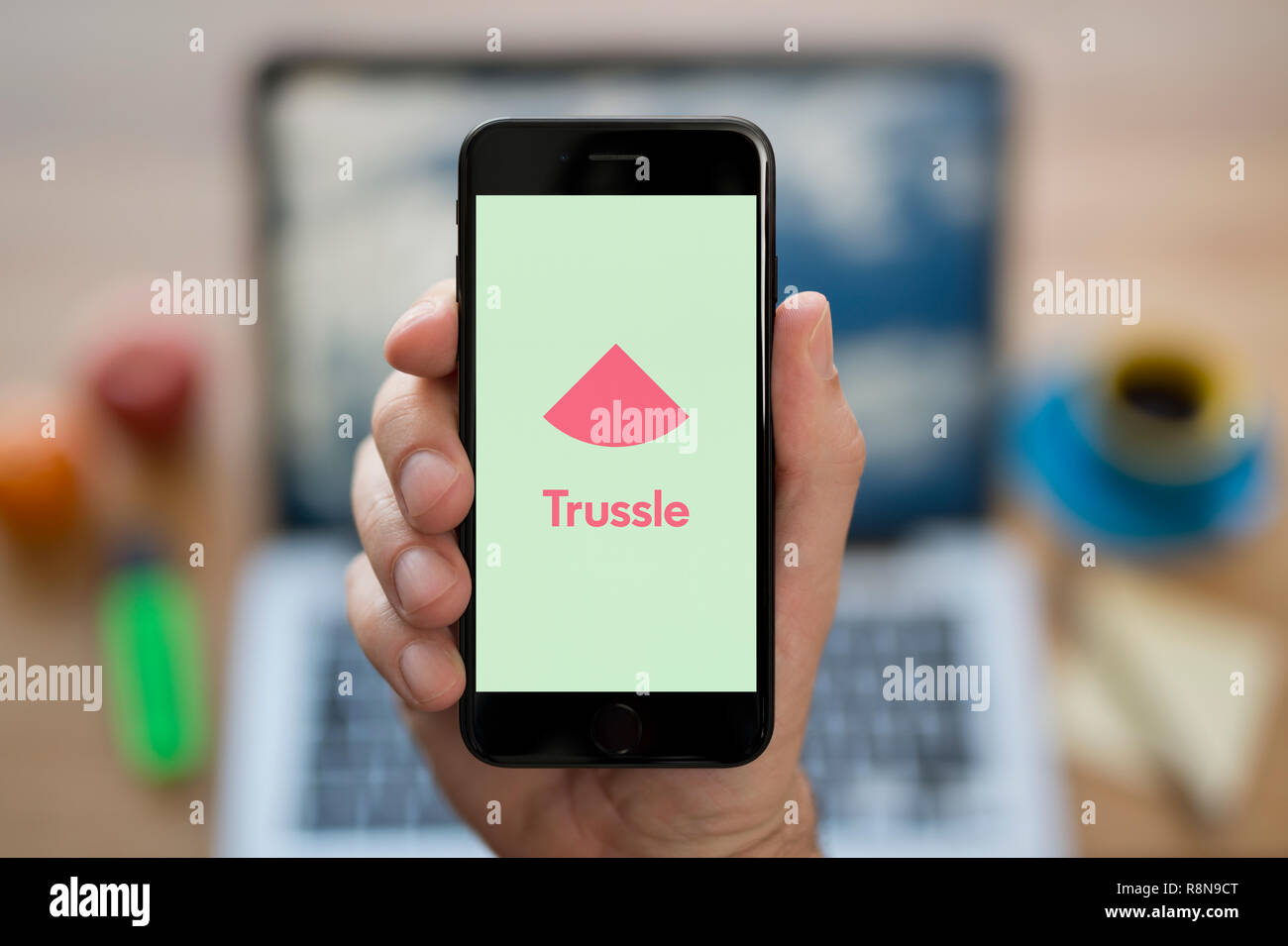 Ein Mann schaut auf seinem iPhone die zeigt die Trussle Logo (nur redaktionelle Nutzung). Stockfoto
