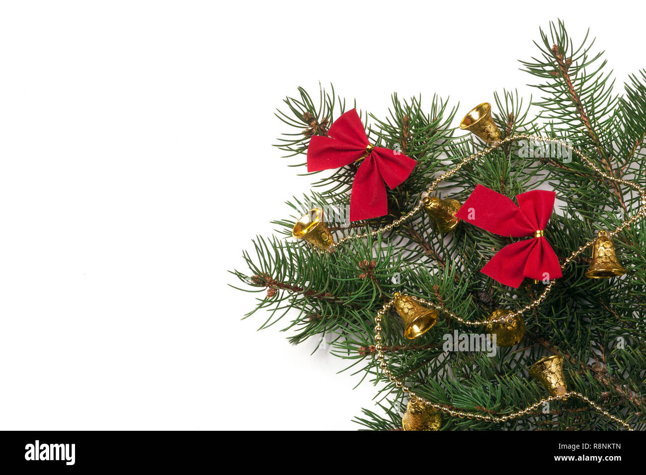 Zweig der Weihnachtsbaum mit kurzen Nadeln dekoriert Glocken und Bögen auf weißem Hintergrund Stockfoto