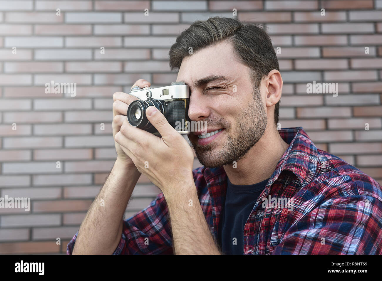 Mann mit retro Foto Kamera Mode Reisen Lebensstil im Freien gegen Mauer Hintergrund. Stockfoto