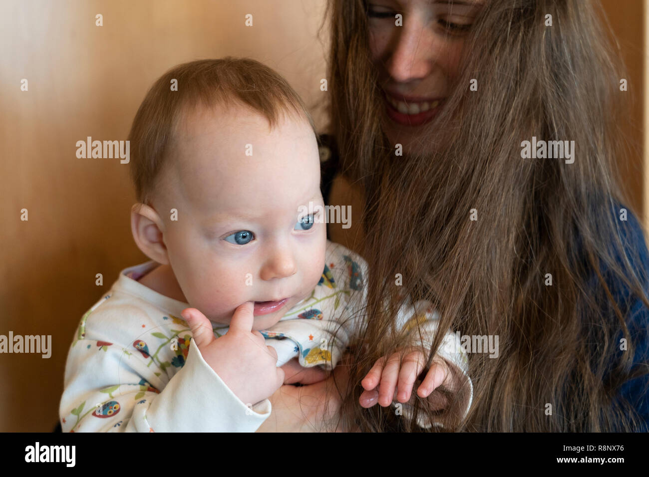 Ein Mädchen von ihrer Mutter gehalten und spielen mit Haar der Mutter mit ihrer Mutter an ihrem Lächeln Stockfoto