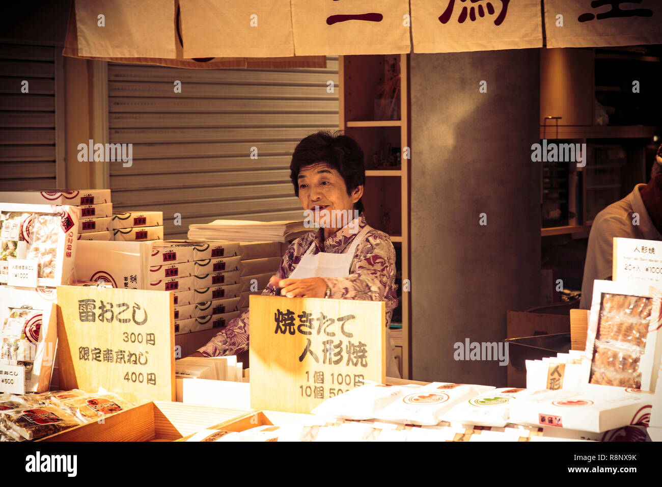 Eine ältere japanische Frau Verkauf von Snacks auf nakamise-dōri in der Nähe von Sensō-ji in Tokio, Japan. Stockfoto