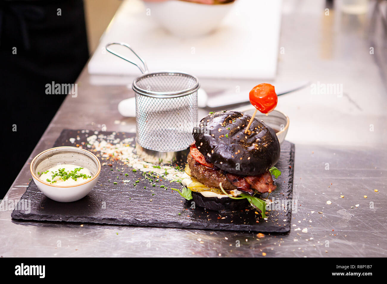 Schwarz Burger mit Pommes frites auf Stein Schneidebrett. In der Küche Restaurant Stockfoto