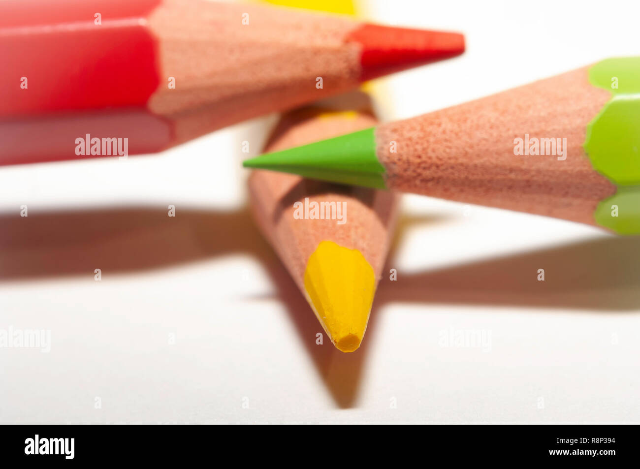 Makro von rot gelb grün Buntstifte, übereinander auf weißem Papier. Stockfoto