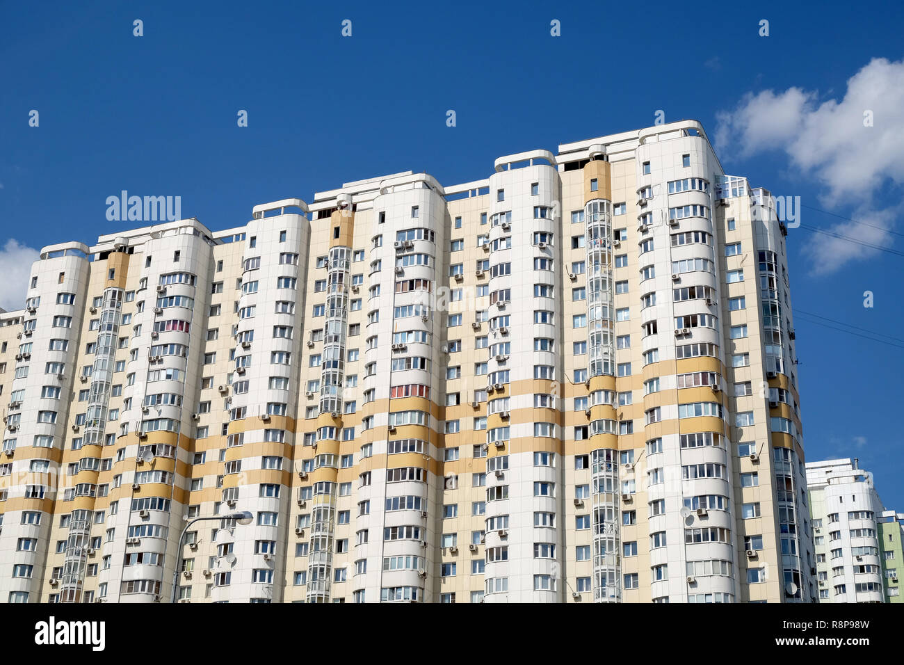 Fassade des hoch modernen beigefarbenen Wohngebäuden auf blauen Himmel mit weißen Wolken vertikale Ansicht Stockfoto