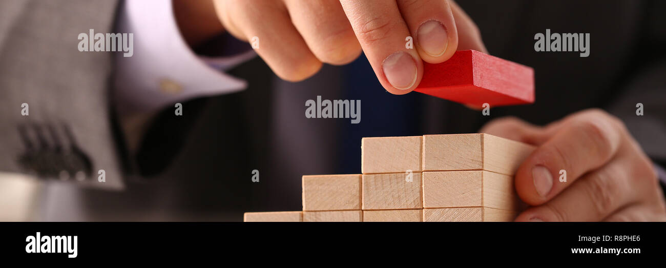 Männliche Hand hält aus rotem Holz Block der Treppe Stockfoto